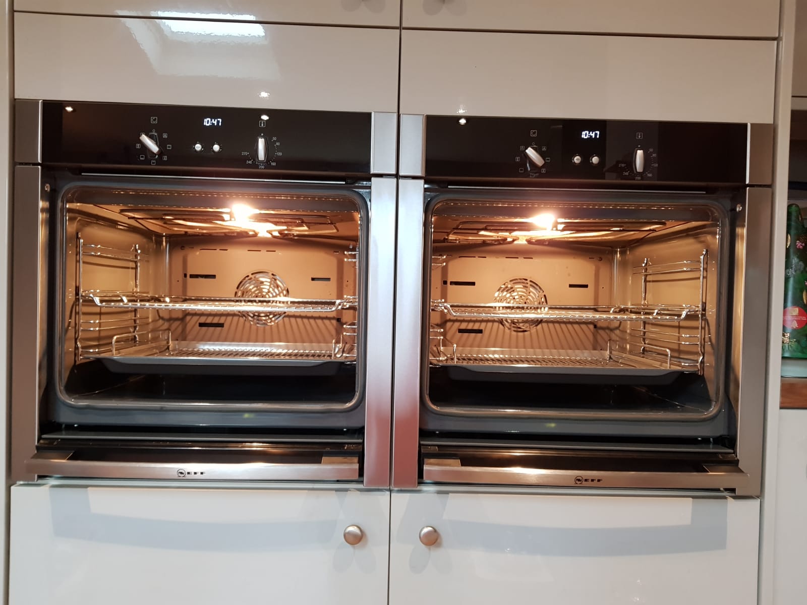 Double built-in ovens open with lights on and clean cavities