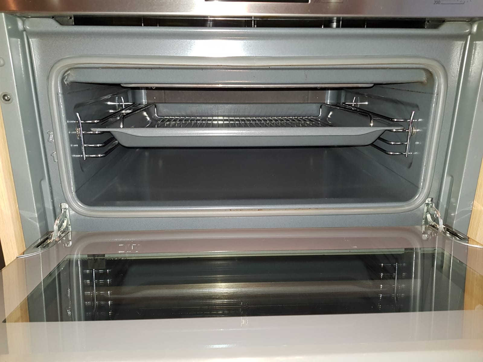 Close-up of a clean oven cavity with door open and bright metal surfaces