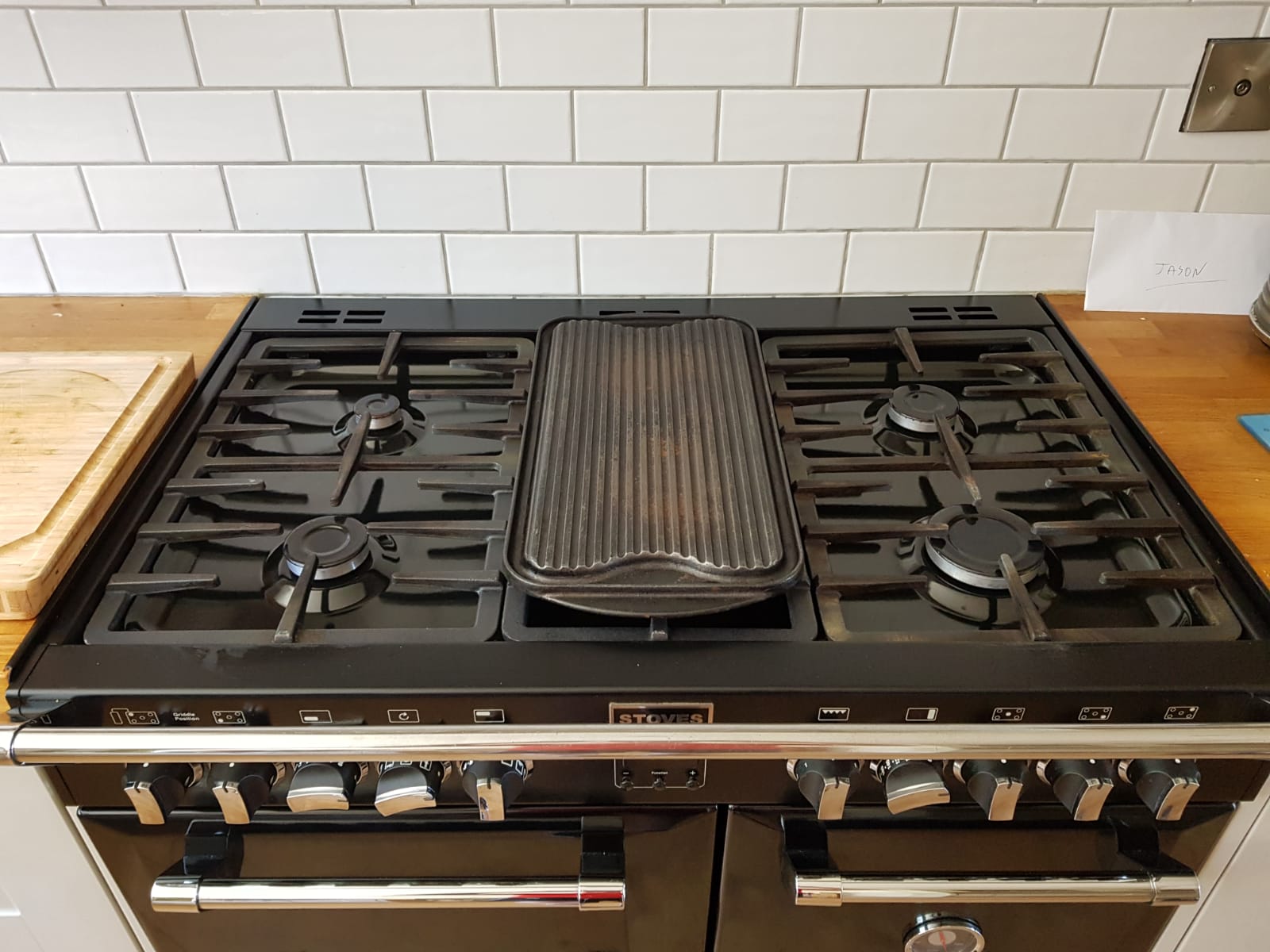 Top-down view of a clean black range hob with gas burners and griddle