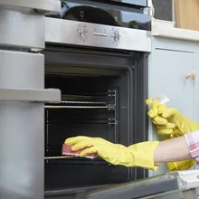 Gloved hand wiping inside an oven during a clean